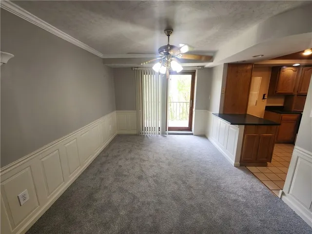 an empty room with chandelier fan and windows