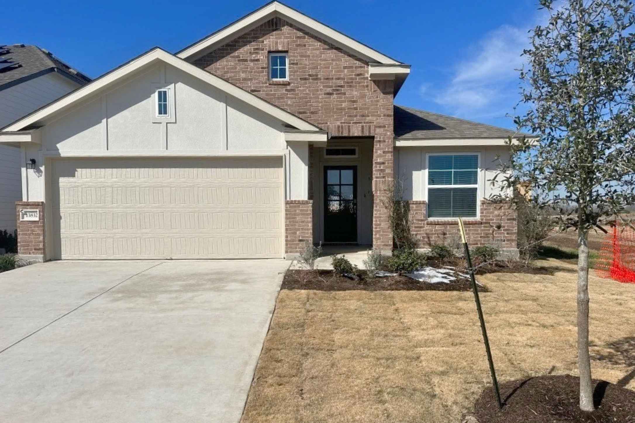 View of front facade featuring brick siding, concrete driveway, a front lawn, and a garage