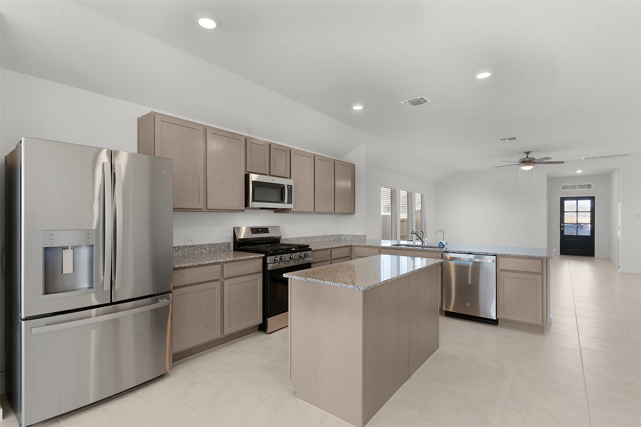 13832 Scarlett Song Drive Elgin, TX 78621 - Photo 7 of 26 Kitchen with stainless steel appliances, a peninsula, a center island, light stone countertops, and recessed lighting