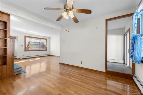 a view of an empty room with a window and wooden floor