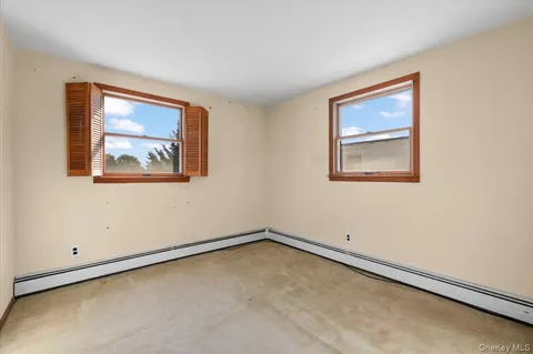 an empty room with a painting and a window