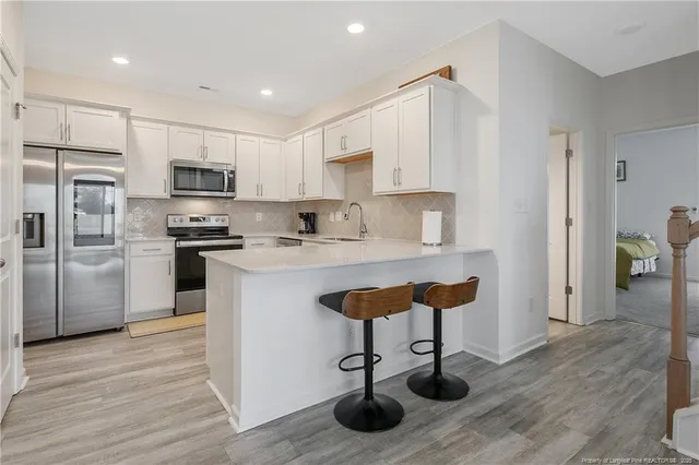 a kitchen with kitchen island stainless steel appliances a sink cabinets and wooden floor