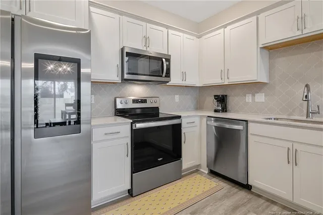a kitchen with white cabinets stainless steel appliances and sink