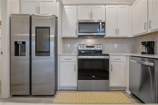 a kitchen with stainless steel appliances granite countertop a refrigerator a stove and a sink