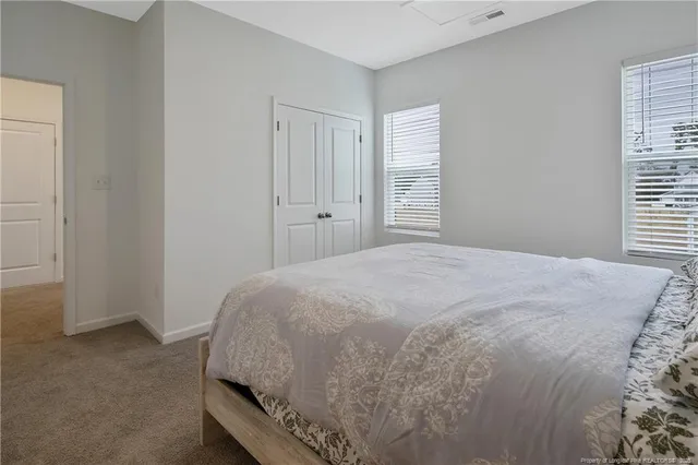 a bed sitting in a bedroom next to a window and dresser
