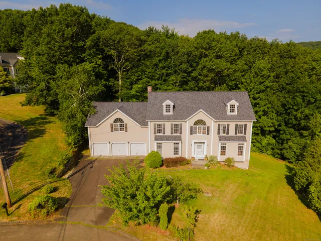 a view of a big house with a big yard and large trees
