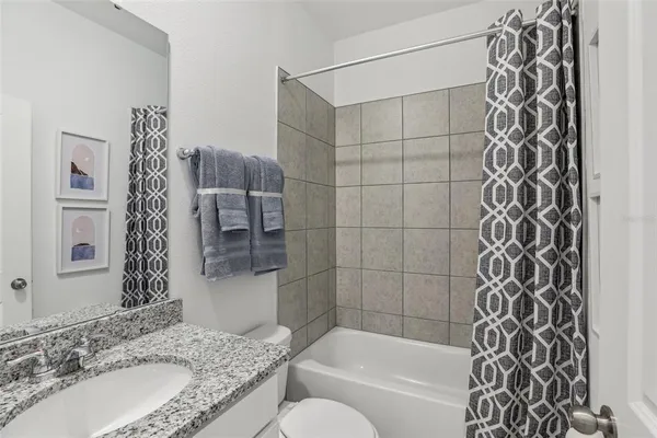 a bathroom with a granite countertop bathtub sink vanity and shower