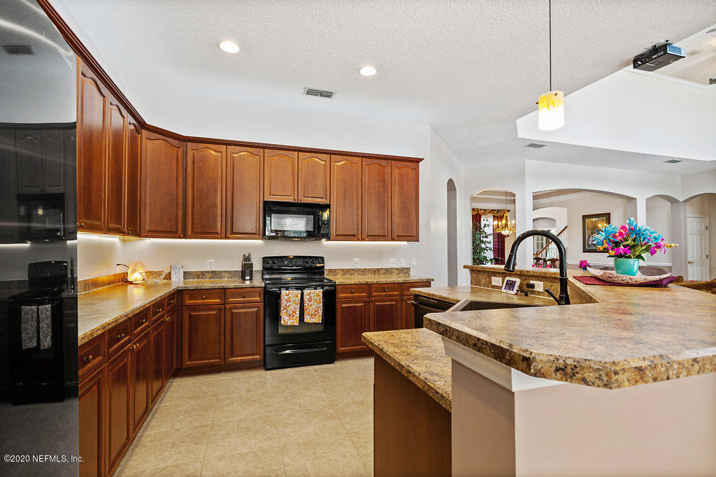 3824 Reds Gait Lane Jacksonville, FL 32223 - Photo 16 of 68 a kitchen with kitchen island granite countertop a stove top oven microwave and refrigerator