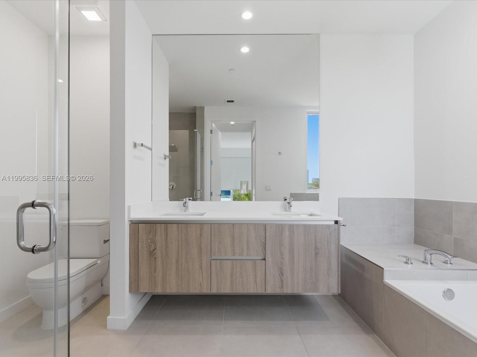 529 Southwest 11th Street, Unit 303 Miami, FL 33129 - Photo 17 of 35 a bathroom with a double vanity sink mirror and bathtub