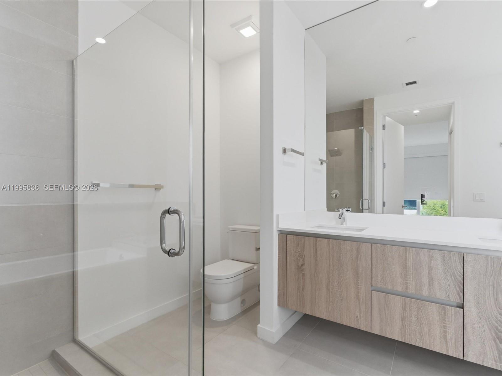529 Southwest 11th Street, Unit 303 Miami, FL 33129 - Photo 19 of 35 a bathroom with a double vanity sink toilet and shower