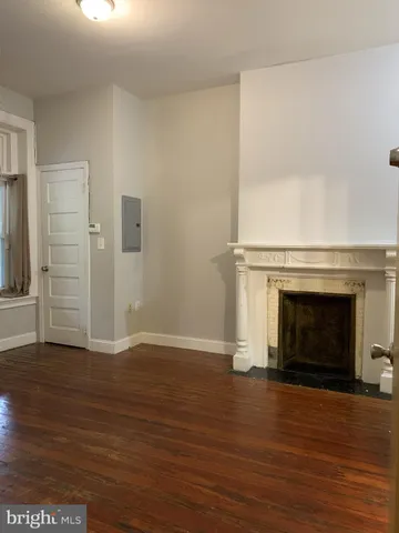 an empty room with wooden floor fireplace and windows
