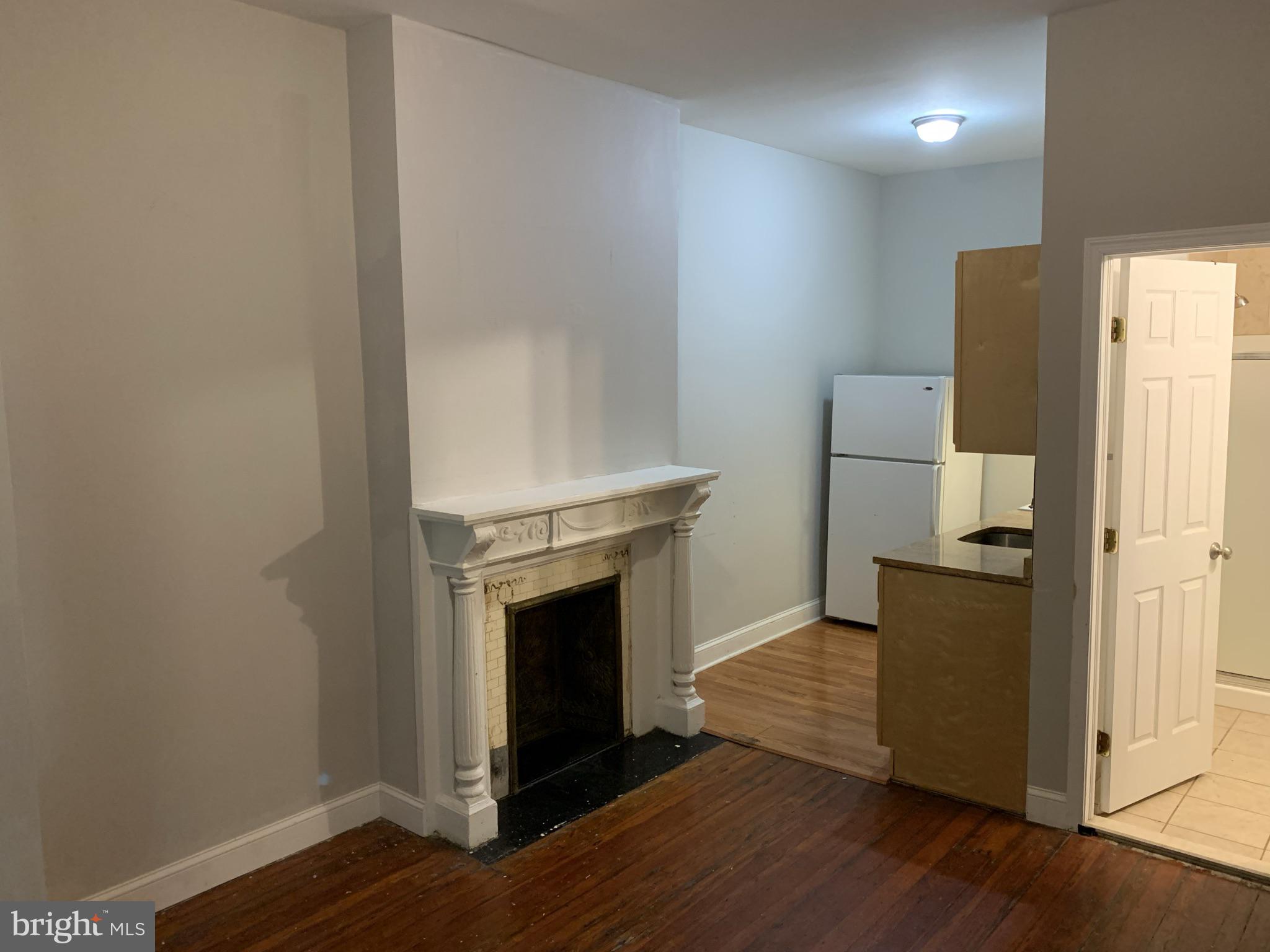 4437 Chestnut Street, Unit 1F Philadelphia, PA 19104 - Photo 7 of 15 a view of a livingroom with wooden floor a fireplace and entryway