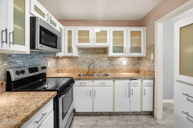 a kitchen with granite countertop white cabinets stainless steel appliances and a sink