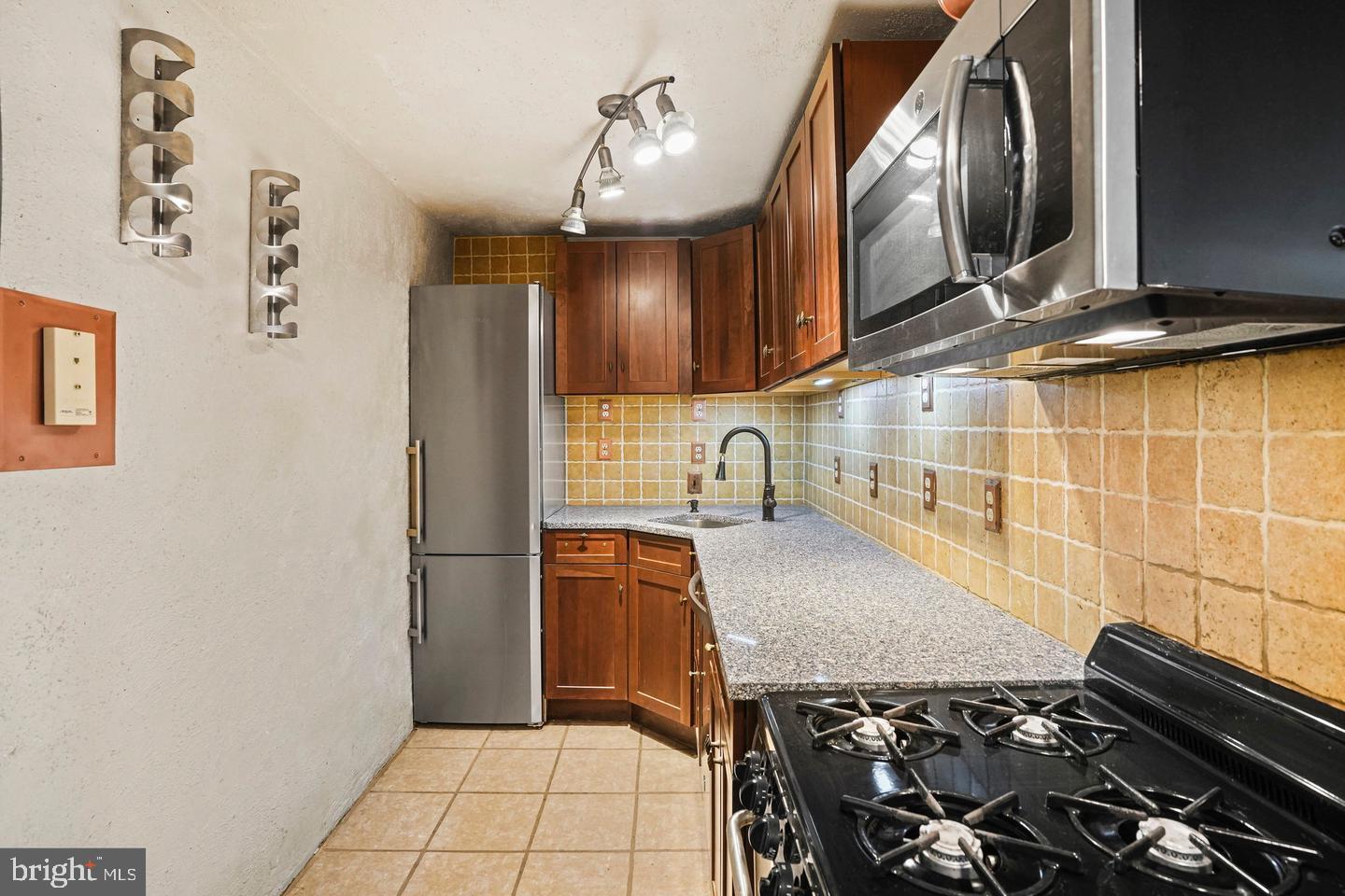 575 Thayer Avenue, Unit 404 Silver Spring, MD 20910 - Photo 9 of 26 a kitchen with granite countertop a stove and a sink
