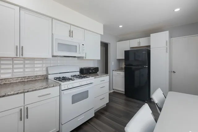 a kitchen with a refrigerator stove and white cabinets