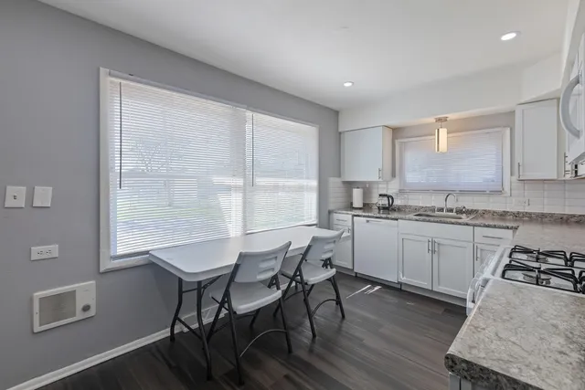 a kitchen with a table chairs a sink dishwasher window and cabinets
