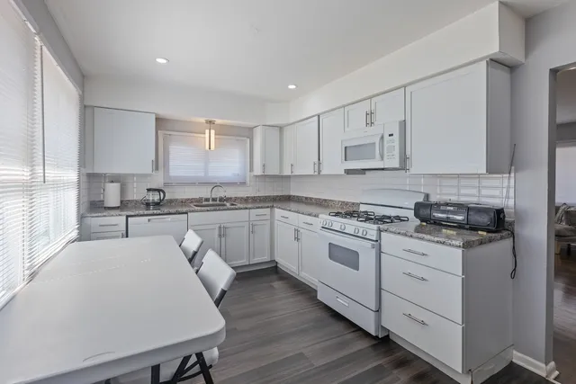 a kitchen with granite countertop white cabinets and white appliances