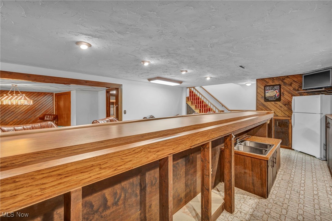 36350 Bainbridge Road Solon, OH 44139 - Photo 21 of 38 Bar with sink, wood counters, white refrigerator, a textured ceiling, and wooden walls