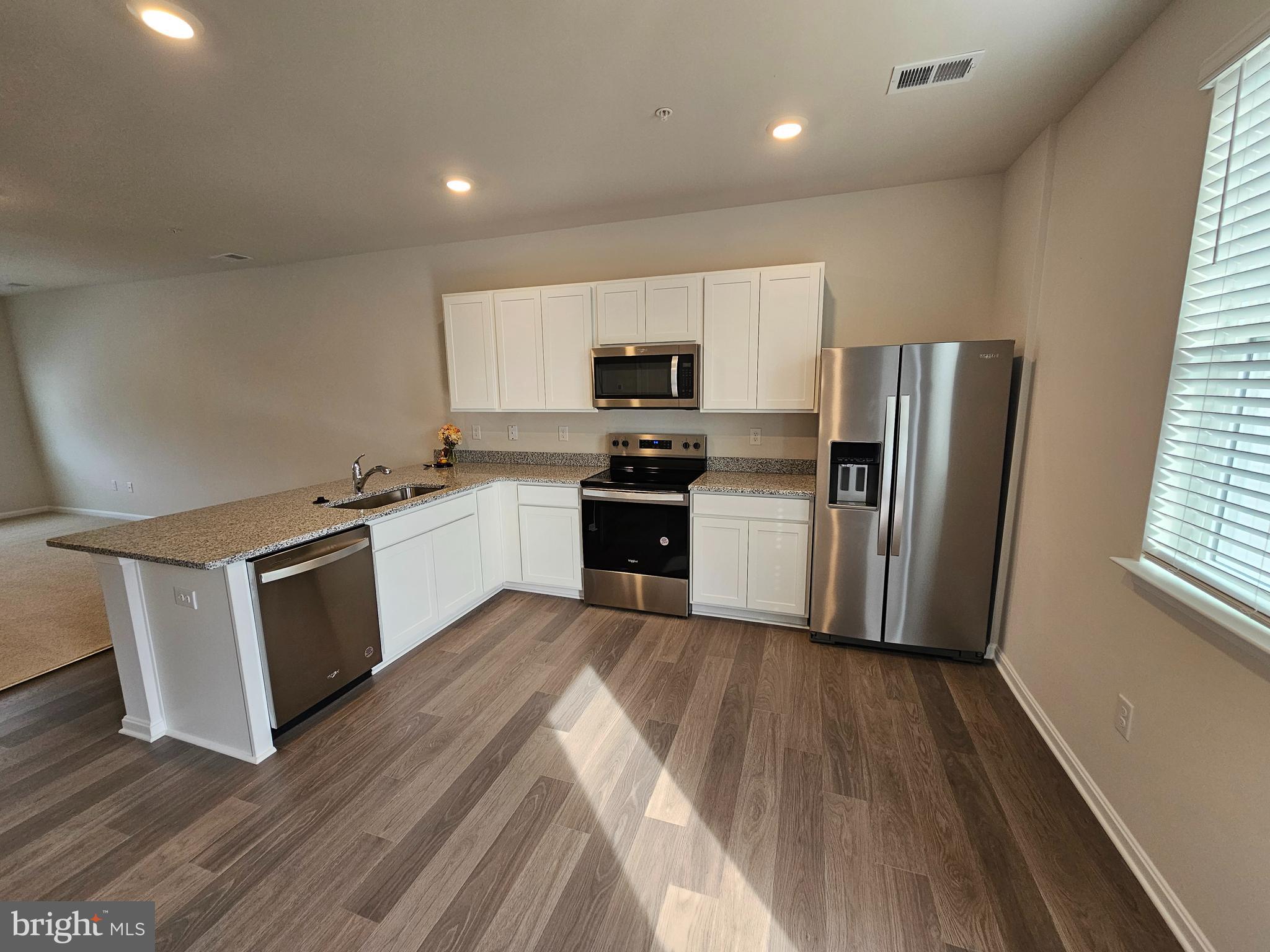 1509 Avon Way Salisbury, MD 21801 - Photo 2 of 19 a kitchen with wooden floors and white stainless steel appliances