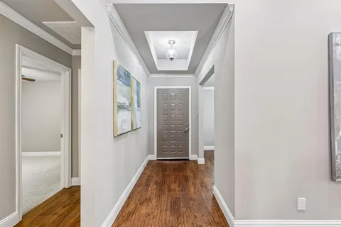 a view of a hallway with wooden floor and a bathroom