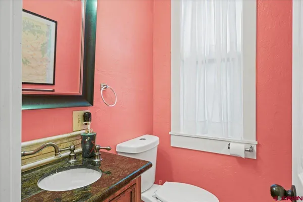 a bathroom with a granite countertop toilet sink and mirror