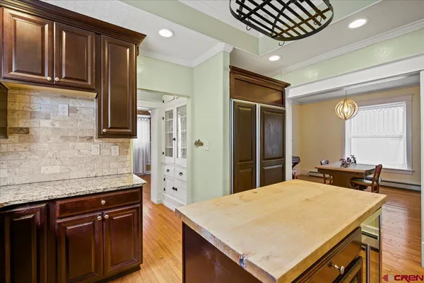 a kitchen with stainless steel appliances kitchen island granite countertop a refrigerator a sink dishwasher and wooden cabinets with a granite countertops