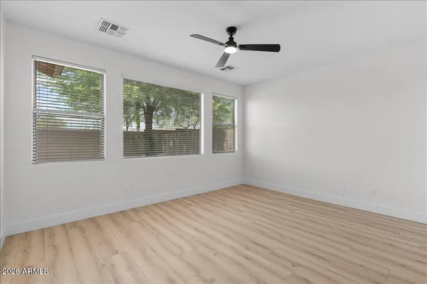 a view of empty room with wooden floor and fan