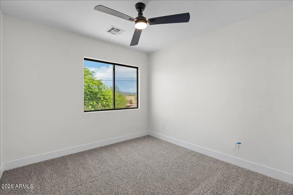 an empty room with a window and a fan