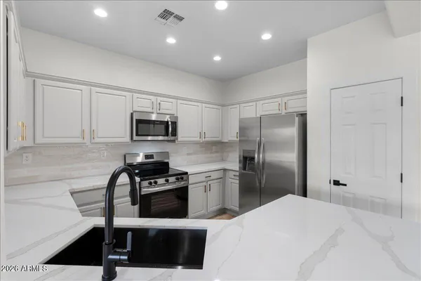a kitchen with a refrigerator a microwave and white cabinets
