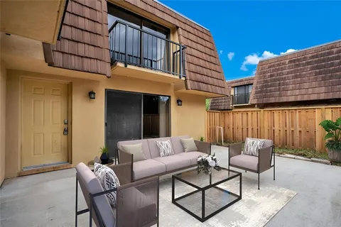 a view of a patio with couches table and chairs and potted plants