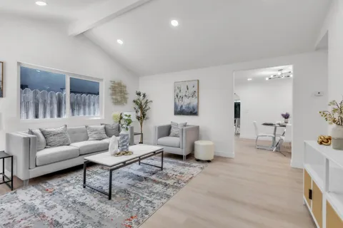 a living room with furniture a fireplace a flat screen tv and a large window