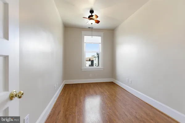 a view of empty room with wooden floor and fan