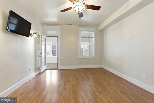 an empty room with wooden floor fan and windows