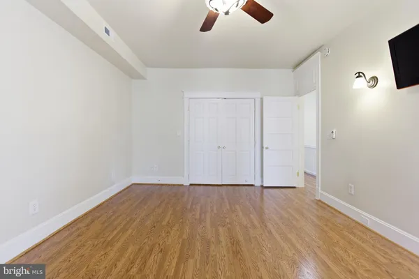 an empty room with ceiling fan and wooden floor