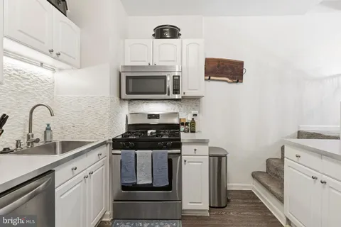 a kitchen with stainless steel appliances a stove microwave and sink