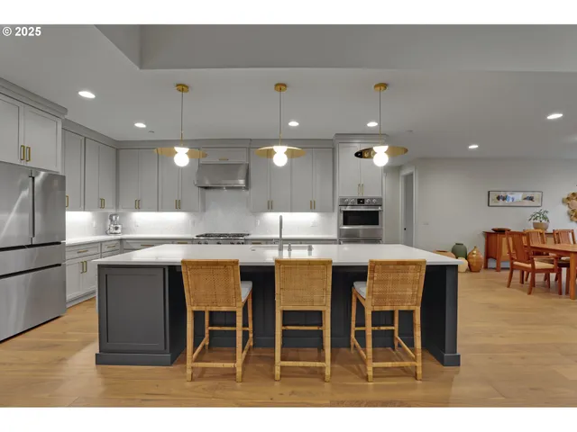 a kitchen with stainless steel appliances kitchen island granite countertop a table chairs and a refrigerator