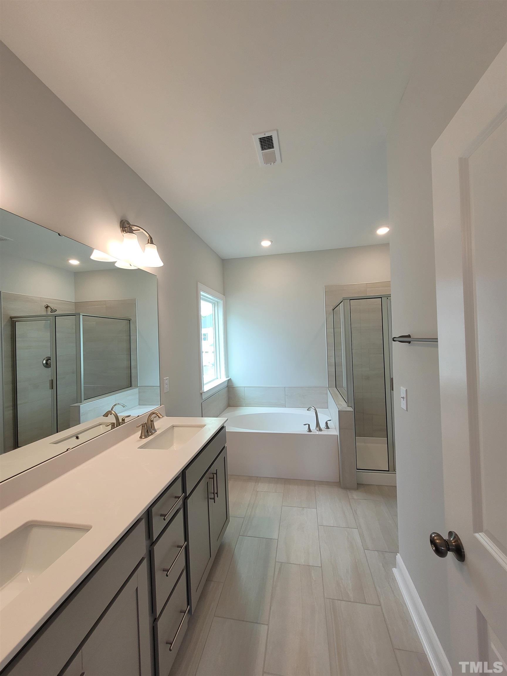 124 Trailing Bluff Way Garner, NC 27529 - Photo 19 of 21 a bathroom with a double vanity sink a large mirror and a bathtub