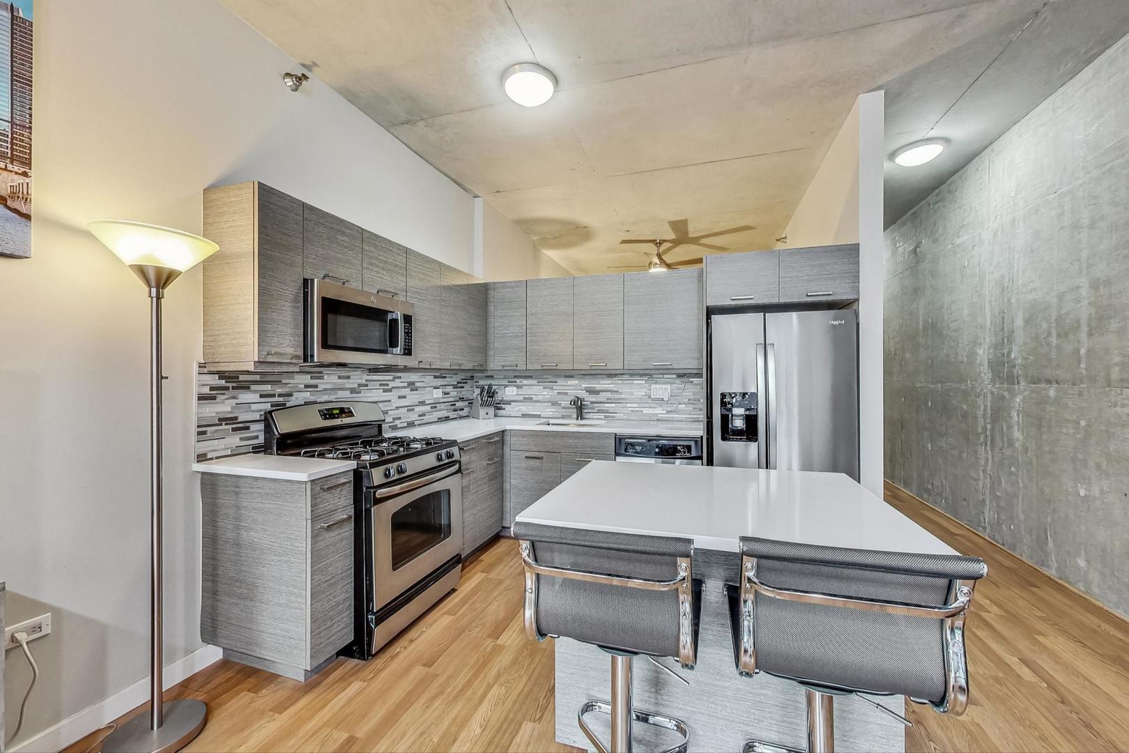235 West Van Buren Street, Unit 1517 Chicago, IL 60607 - Photo 3 of 15 a kitchen with stainless steel appliances a stove a sink island and a refrigerator