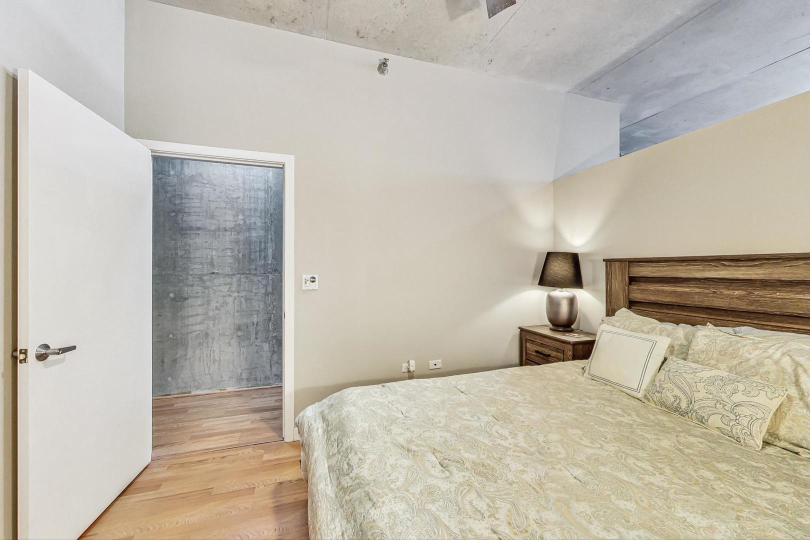 235 West Van Buren Street, Unit 1517 Chicago, IL 60607 - Photo 9 of 15 a bedroom with a bed and lamp