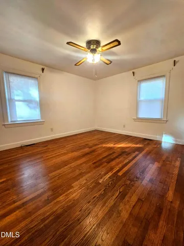 a view of an empty room with window and wooden floor