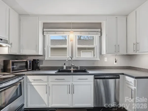 a kitchen with granite countertop a sink and white cabinets