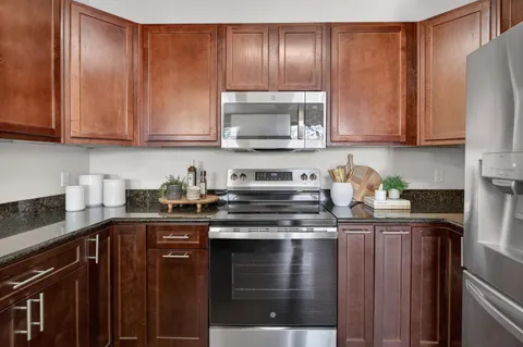 a kitchen with granite countertop wood cabinets stainless steel appliances and a sink