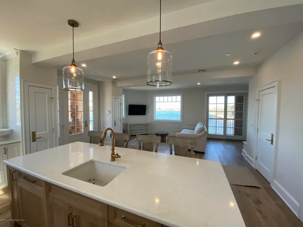 a large kitchen with kitchen island a stove a sink dishwasher a dining table and chairs with wooden floor