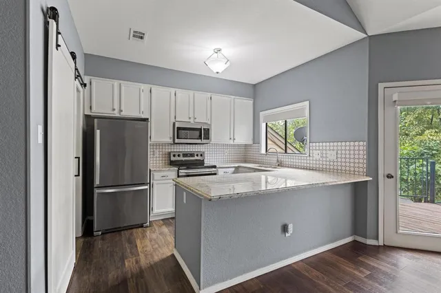 a kitchen with stainless steel appliances wooden floors and white cabinets