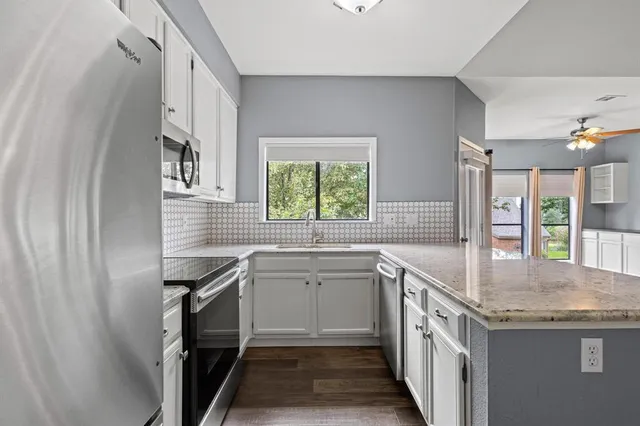 a kitchen with stainless steel appliances granite countertop a refrigerator a stove a sink and a refrigerator