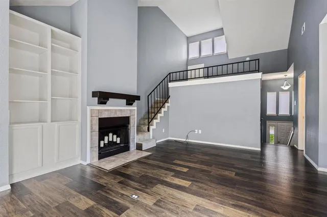 a view of an empty room with wooden floor fireplace and a window