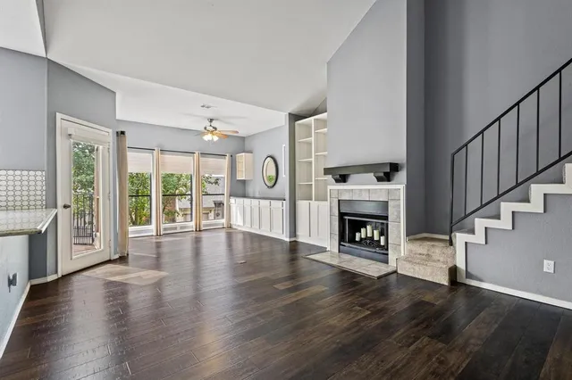 a view of an empty room with wooden floor fireplace and a window