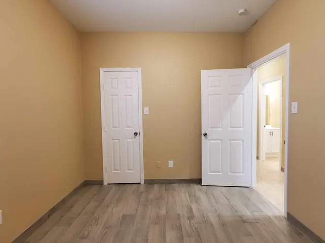 a view of an empty room with closet and wooden floor