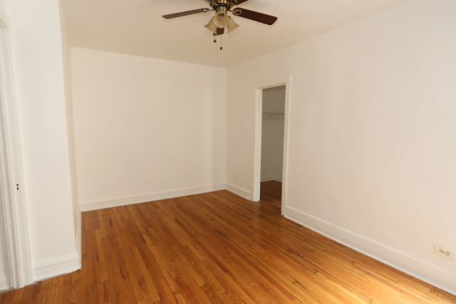 4604 North Beacon Street, Unit 3E Chicago, IL 60640 - Photo 6 of 13 an empty room with wooden floor ceiling fan and window