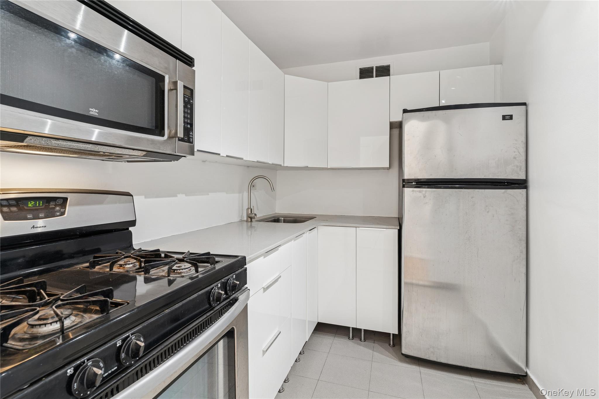 102-10 66th Road, Unit 20G Queens, NY 11375 - Photo 8 of 14 Kitchen featuring stainless steel appliances & white cabinetry
